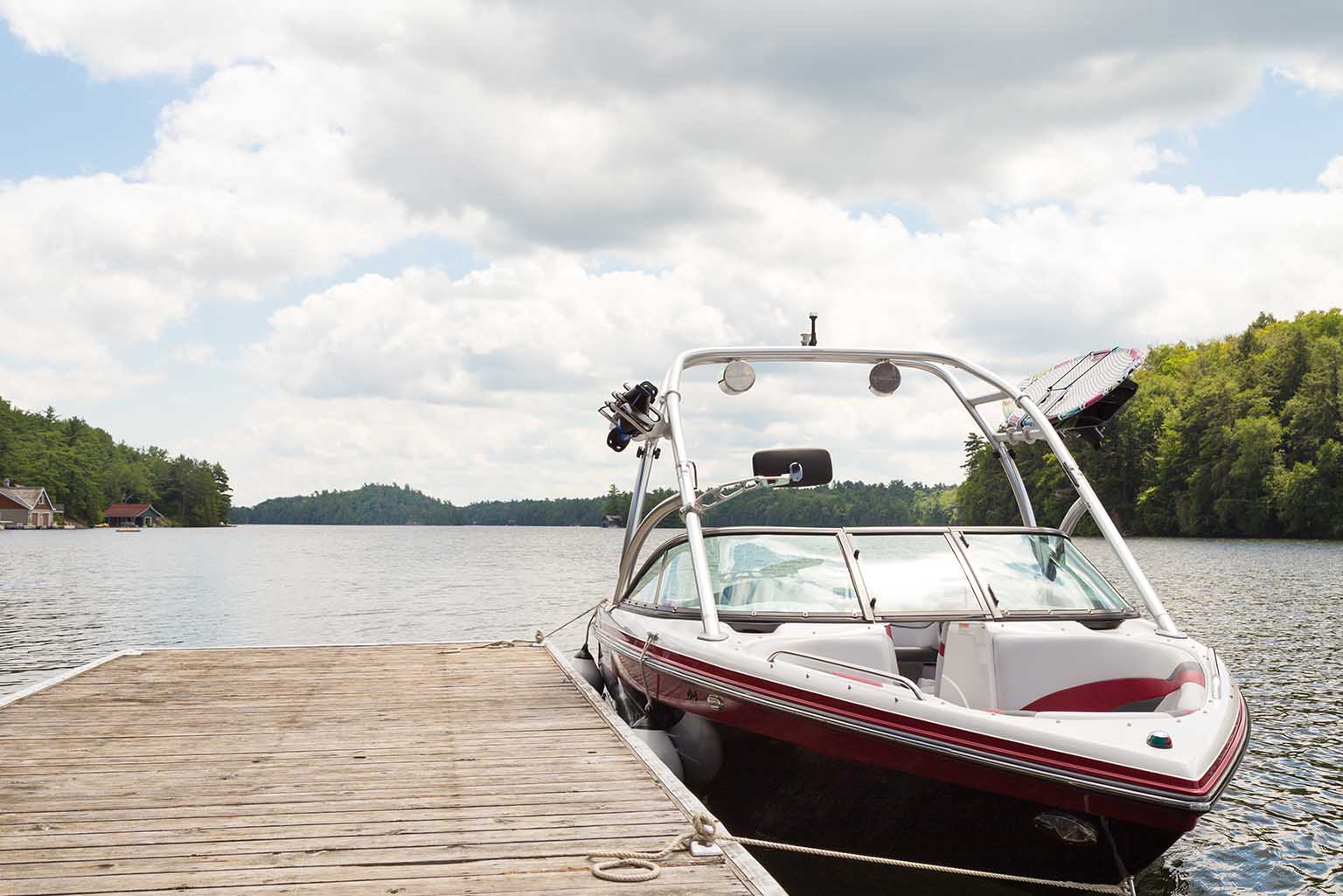 A sleek motorboat docked on a wooden pier at a serene lake -  https://www.rf-ins.com/